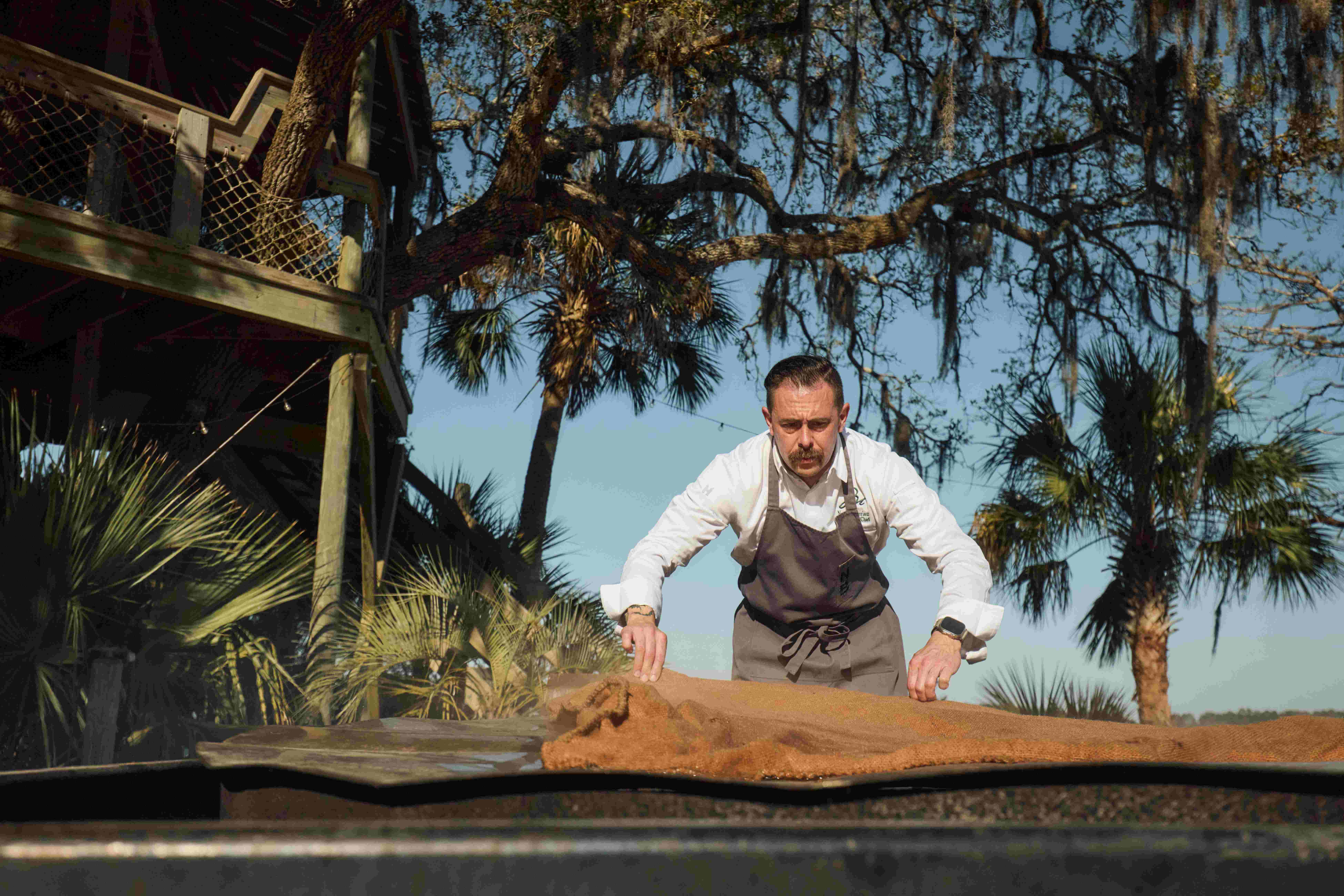 A man dumping oysters out of a burlap sack onto a table at Montage Palmetto Bluff oyster roast